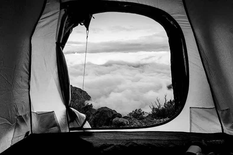 Blick aus einem Zelt auf wolkenverhangende Berge